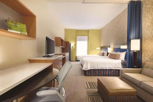 Home2 Suites by Hilton Parc Lafayette في لافاييت: غرفة في الفندق مع غرفة نوم مع سرير وأريكة
