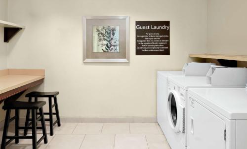 a laundry room with a washing machine and stools at Homewood Suites Lafayette-Airport in Lafayette