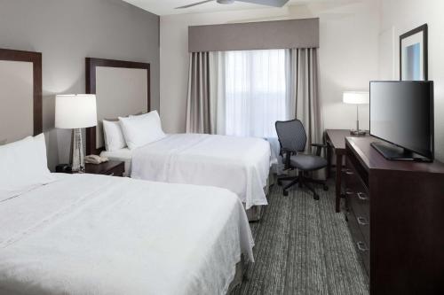 a hotel room with two beds and a desk with a television at Homewood Suites by Hilton Mahwah in Mahwah