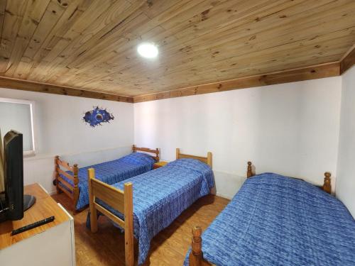 a bedroom with two beds and a tv and wooden ceilings at Arriendo Los Vilos, Central in Los Vilos
