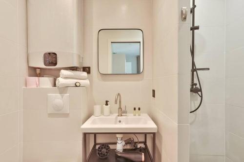une salle de bain blanche avec un lavabo et un miroir dans l'établissement Cozy and practical apt in 10th arr - PARIS, à Paris