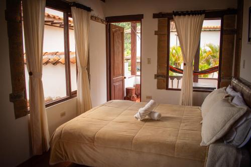 a bedroom with a large bed with two windows at El Pozzo Hotel Campestre in Villa de Leyva