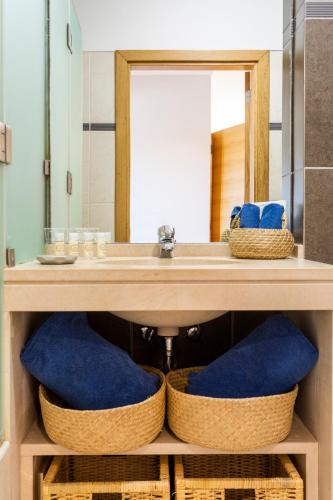 a bathroom with a sink and a mirror and baskets at Placid Village in Carvoeiro