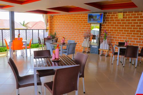 un restaurante con mesas y sillas y una pared de ladrillo en Jatheo Hotel Rwentondo en Mbarara