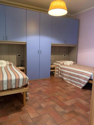 Habitación con 2 camas, armarios morados y suelo de baldosa. en Dall’Artemio - appartamento a Sillico, en Sillico