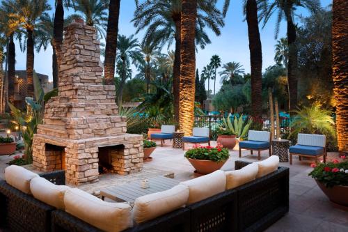 d'une terrasse avec une cheminée en pierre, des chaises et des palmiers. dans l'établissement DoubleTree by Hilton Paradise Valley Resort Scottsdale, à Scottsdale