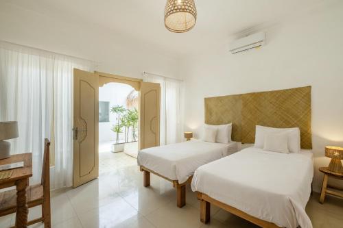 two beds in a white room with a window at The Warm Sun - Bingin in Uluwatu