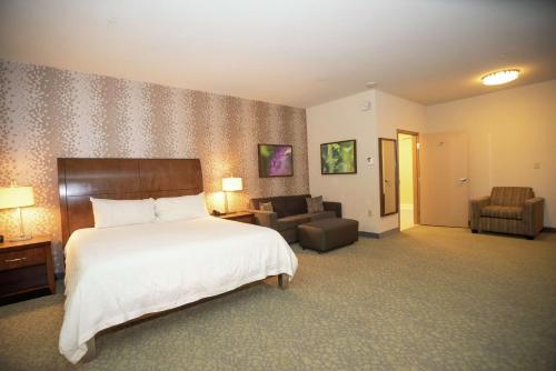 a hotel room with a bed and a living room at Hilton Garden Inn Covington/Mandeville in Covington