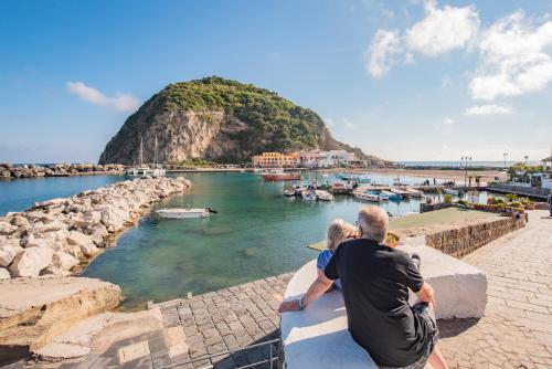 two people sitting on a wall looking at the water at Hotel Villa Sirena in Ischia