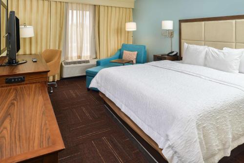 Habitación de hotel con cama, TV y silla en Hampton Inn Vero Beach Outlets en Vero Beach