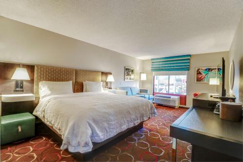 ラスベガスにあるHampton Inn Tropicanaの大きなベッドとデスクが備わるホテルルームです。