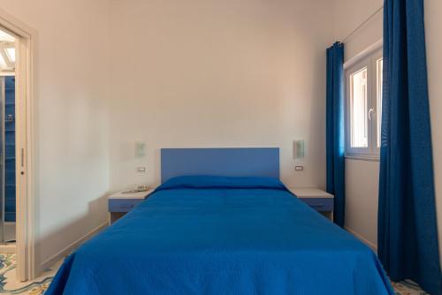 a blue bed in a white room with a window at Hotel Villa Sirena in Ischia