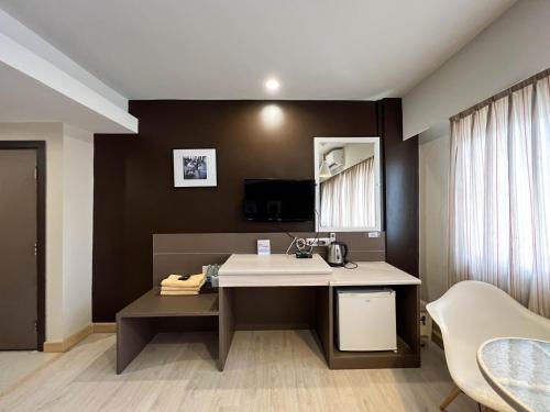 a bathroom with a sink and a desk with a mirror at Srivichai Hotel in Nakhon Ratchasima