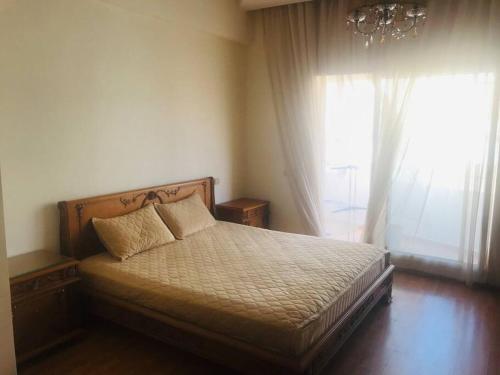 1 dormitorio con 1 cama con lámpara de araña y ventana en Appartement à perle de Nouaceur en Nouaceur