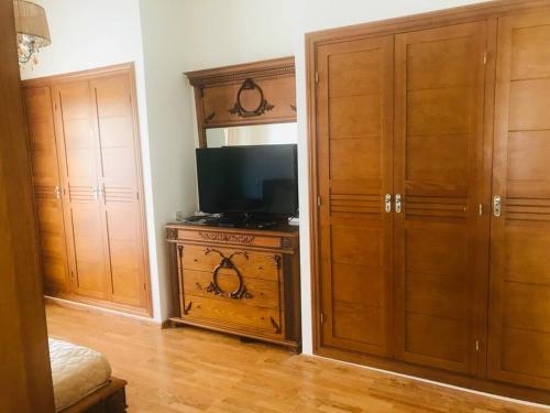 Habitación con TV y algunos armarios de madera. en Appartement à perle de Nouaceur en Nouaceur