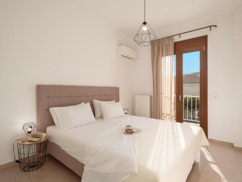 a white bedroom with a white bed with a window at Porto Kaza in Sitia