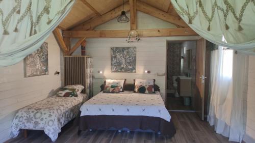 a bedroom with two beds and a wooden ceiling at La vallée des noyers in Beaulieu