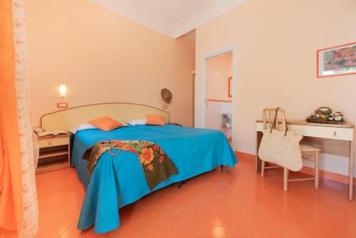 a bedroom with a blue bed and a desk at Hotel Villa Sirena in Ischia
