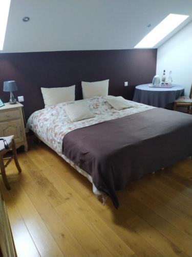 Un dormitorio con una cama grande y una mesa. en A la maison du Bonheur, en Lanty-sur-Aube