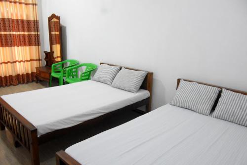 two beds in a room with green chairs at Green Mart Family Rest in Anuradhapura