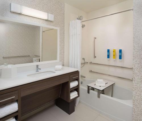 y baño con lavabo, bañera y espejo. en Home2 Suites By Hilton Ft. Lauderdale Downtown, Fl en Fort Lauderdale