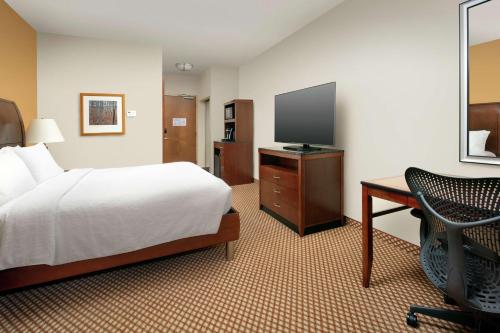 a hotel room with a bed and a desk and a television at Hilton Garden Inn Odessa in Odessa
