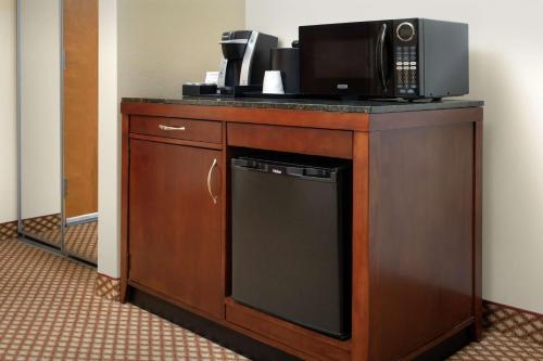 a microwave sitting on top of a wooden cabinet with a dishwasher at Hilton Garden Inn Odessa in Odessa