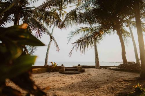 dos personas sentadas en una playa con palmeras en Amuura Beach Villa en Beruwala