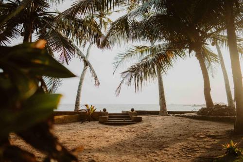 two people sitting on a beach with palm trees at Amuura Beach Villa in Beruwala