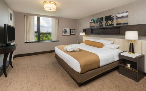 a bedroom with a large bed and a flat screen tv at The Saratoga Hilton in Saratoga Springs
