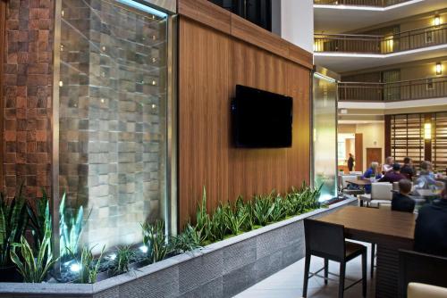 a restaurant with a tv on a wall with plants at Embassy Suites by Hilton Portland Tigard in Tigard