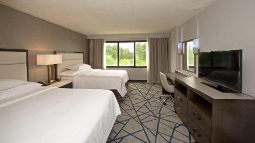 a hotel room with two beds and a flat screen tv at Embassy Suites by Hilton Portland Washington Square in Tigard