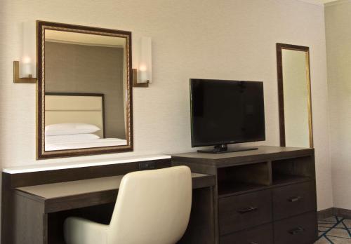 a room with a desk with a television and a mirror at Embassy Suites by Hilton Portland Tigard in Tigard