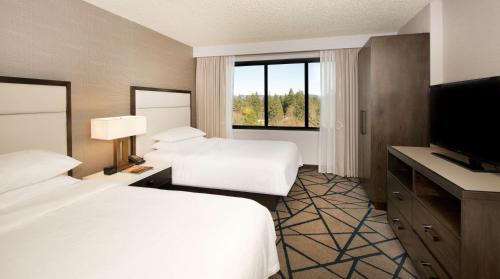 a hotel room with two beds and a flat screen tv at Embassy Suites by Hilton Portland Tigard in Tigard