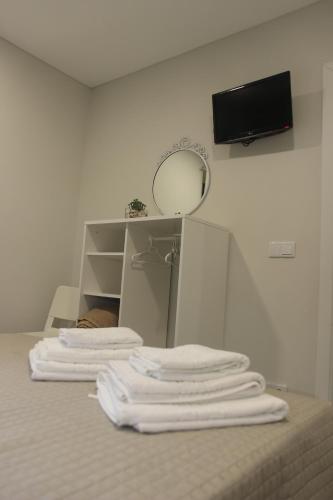 a group of white towels sitting on top of a bed at Casa D'Alegria in Ponta Delgada