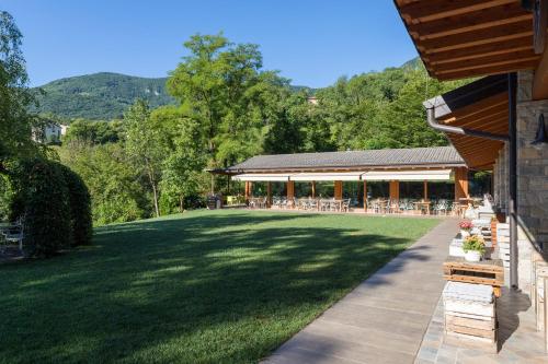 a patio with a lawn and a building with mountains in the background at Agriturismo Scuderia della Valle in Valsecca