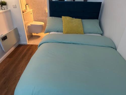 łóżko z niebieskim zagłówkiem w sypialni w obiekcie Nice and Cosy Studio w Bristolu