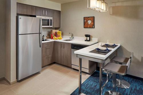 a kitchen with a white refrigerator and a table at Homewood Suites by Hilton San Diego Hotel Circle/SeaWorld Area in San Diego