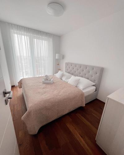 a white bedroom with a large bed and a window at Slnečný dom pri jazere in Hrubá Borša