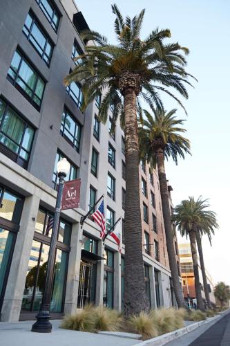 a building with palm trees in front of it at Tapestry By Hilton The Fort Sutter Hotel Sacramento, Ca in Sacramento