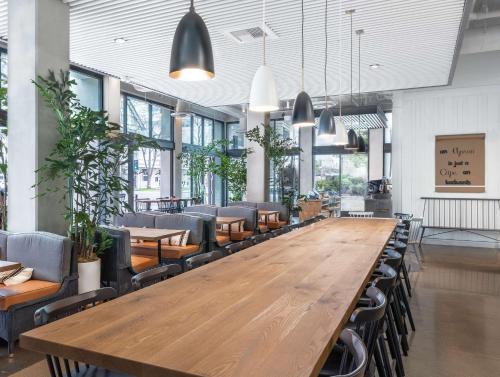 a large wooden table in a restaurant with chairs at Tapestry By Hilton The Fort Sutter Hotel Sacramento, Ca in Sacramento