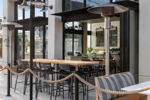 a restaurant with a wooden table and chairs at Tapestry By Hilton The Fort Sutter Hotel Sacramento, Ca in Sacramento
