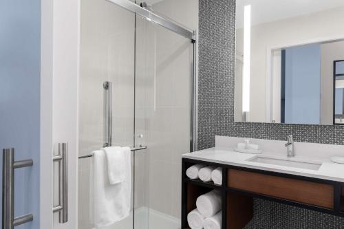 a bathroom with a shower and a sink and a mirror at Tapestry By Hilton The Fort Sutter Hotel Sacramento, Ca in Sacramento
