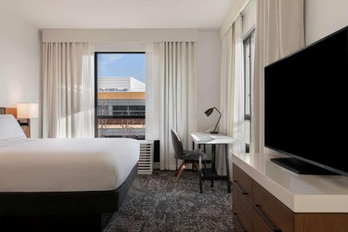 a hotel room with a bed and a flat screen tv at Tapestry By Hilton The Fort Sutter Hotel Sacramento, Ca in Sacramento