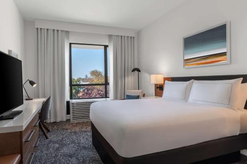 a hotel room with a large bed and a window at Tapestry By Hilton The Fort Sutter Hotel Sacramento, Ca in Sacramento
