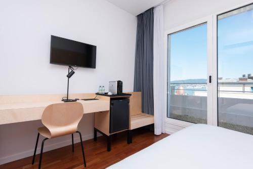 a hotel room with a desk with a computer and a window at Hotel Maroa Vigo in Vigo