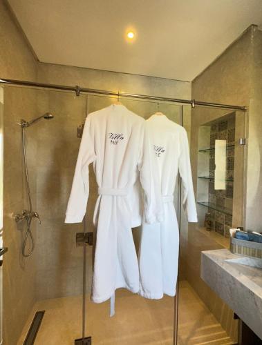 2 albornoces blancos colgados en un baño con cabina de ducha de cristal en Villa Jne Marrakech en Oulad Mazoug