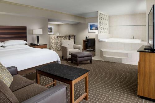 um quarto de hotel com uma cama e uma banheira em Hilton Charlotte University Place em Charlotte