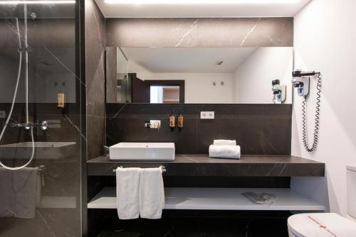 a bathroom with a sink and a toilet and a mirror at Hotel Maroa Vigo in Vigo