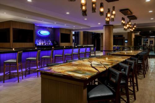 a bar in a restaurant with purple lighting at Hilton Charlotte University Place in Charlotte